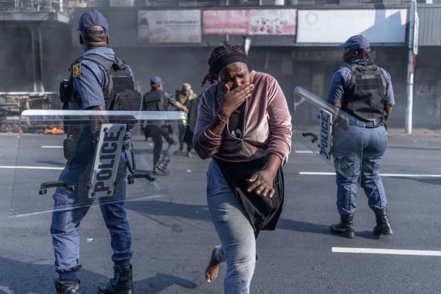 Members of the South African Police (SAPS) assist a visibly shaken residents to take cover after clashes erupt between protesters and foreign nationals in Durban on October 8, 2026. Several vehicles were set alight during the confrontation amid tensions over undocumented immigration and foreign nationals. South African protesters and foreign nationals clashed Thursday, police and an AFP reporter said, as tensions over migration were reignited by a court order that government must restart processing asylum applications.
Violence erupted in Soweto, in Johannesburg, and the east coast port city of Durban, with several cars torched and foreign-run businesses forced to close.
It followed protests called by anti-illegal migration movements that were behind waves of demonstrations earlier this year that led tens of thousands of nationals of other African countries to flee the country. (Photo by RAJESH JANTILAL / AFP)
