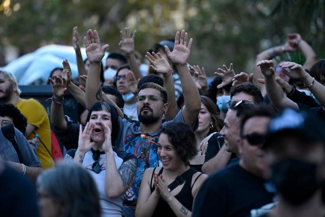 People at a housing rights activists' camp raise their hands and chant slogans ahead of a demonstration called by far-right groups seeking the camp's eviction at City Hall Square in Valencia, eastern Spain, on October 8, 2026. (Photo by Jose JORDAN / AFP)