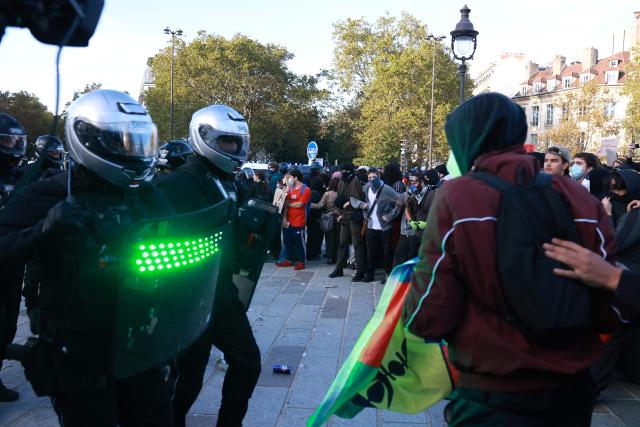 A French police officer of the Repression of Violent Action Motorised Brigade (Brav-M or Brigade de repression de l'action violente motorisee) holds a strobe-capable shield during a demonstration of high-school students at Place de la Bastille, in Paris, on October 8, 2026, as part of a nationwide protest movement over learning conditions. Since late September, pupils have barred the entrances to hundreds of schools, complaining of teacher absences, overloaded timetables, dilapidated classrooms and buildings ill-adapted to rising temperatures, among other grievances. (Photo by Kenzo TRIBOUILLARD / AFP)