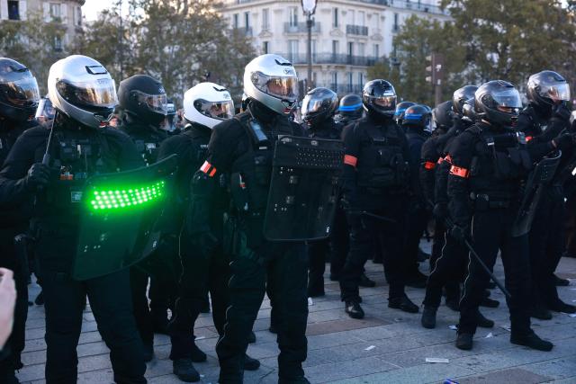 A French police officer of the Repression of Violent Action Motorised Brigade (Brav-M or Brigade de repression de l'action violente motorisee) holds a strobe-capable shield during a demonstration of high-school students at Place de la Bastille, in Paris, on October 8, 2026, as part of a nationwide protest movement over learning conditions. Since late September, pupils have barred the entrances to hundreds of schools, complaining of teacher absences, overloaded timetables, dilapidated classrooms and buildings ill-adapted to rising temperatures, among other grievances. (Photo by Kenzo TRIBOUILLARD / AFP)