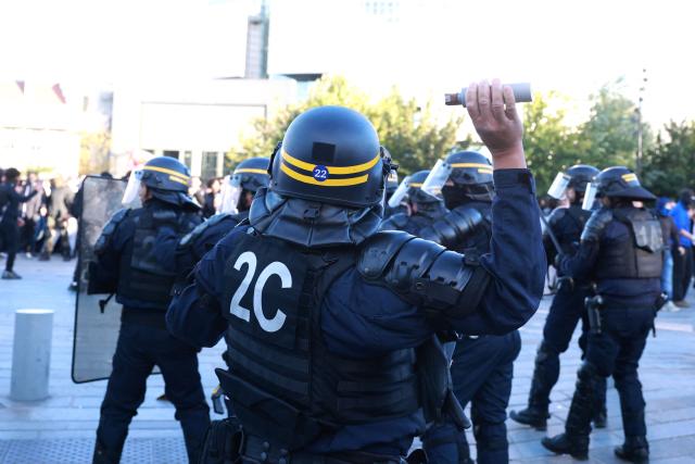 French Republican Security Corps (CRS - Compagnies Republicaines de Securite) police officer throws a tear gas canister during a demonstration of high-school students at Place de la Bastille, in Paris, on October 8, 2026, as part of a nationwide protest movement over learning conditions. Since late September, pupils have barred the entrances to hundreds of schools, complaining of teacher absences, overloaded timetables, dilapidated classrooms and buildings ill-adapted to rising temperatures, among other grievances. (Photo by Kenzo TRIBOUILLARD / AFP)