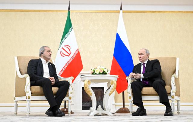 In this pool photograph distributed by the Russian state agency Sputnik, Russia's President Vladimir Putin and Iranian President Masoud Pezeshkian hold a meeting in Turkmenbashi on October 8, 2026. (Photo by Sergei BOBYLYOV / POOL / AFP)
