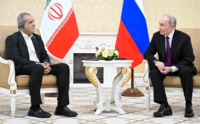 In this pool photograph distributed by the Russian state agency Sputnik, Russia's President Vladimir Putin and Iranian President Masoud Pezeshkian hold a meeting in Turkmenbashi on October 8, 2026. (Photo by Sergei BOBYLYOV / POOL / AFP)