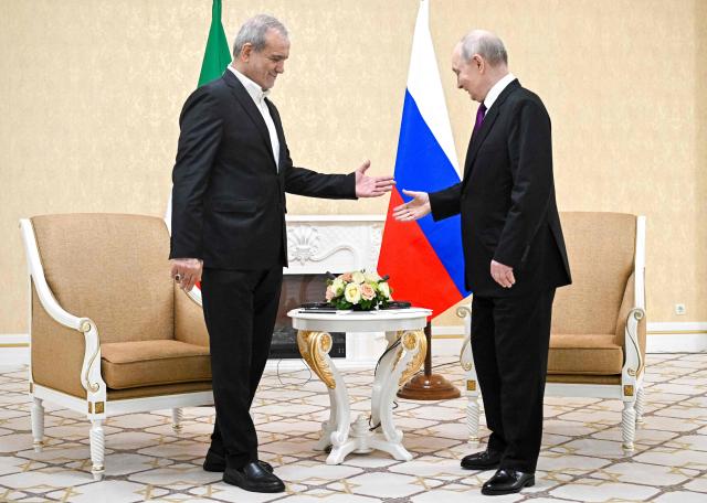 In this pool photograph distributed by the Russian state agency Sputnik, Russia's President Vladimir Putin and Iranian President Masoud Pezeshkian hold a meeting in Turkmenbashi on October 8, 2026. (Photo by Sergei BOBYLYOV / POOL / AFP)