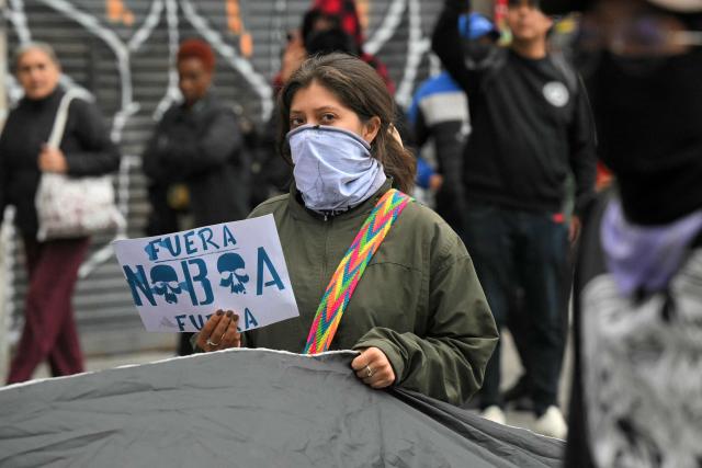A demonstrator holds a placard reading "Noboa Out" during a march organized by Ecuadorean unions and social movements against the government of President Daniel Noboa in Quito on October 8, 2026. (Photo by Rodrigo BUENDIA / AFP)