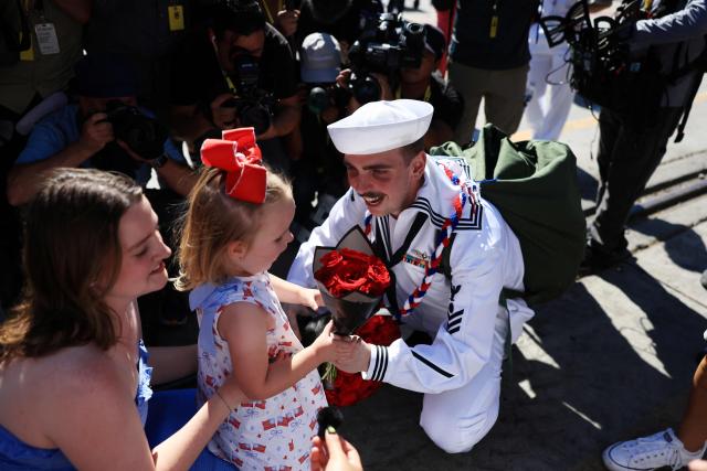 A family is reunited as the US Navy aircraft carrier USS Abraham Lincoln (CVN-72) arrives at Naval Air Station North Island in San Diego, California, on October 8, 2026. The Nimitz-class warship returned from a lengthy, difficult Iran war deployment in which multiple service members in the carrier strike group attempted suicide. The massive nuclear-powered warship left California in November 2025 for duty in the South China Sea and was rerouted to the Middle East before US-Israeli attacks on Iran that began in late February, staying at sea until a Thailand port call in early September. (Photo by David Swanson / AFP)