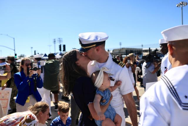 A family is reunited as the US Navy aircraft carrier USS Abraham Lincoln (CVN-72) arrives at Naval Air Station North Island in San Diego, California, on October 8, 2026. The Nimitz-class warship returned from a lengthy, difficult Iran war deployment in which multiple service members in the carrier strike group attempted suicide. The massive nuclear-powered warship left California in November 2025 for duty in the South China Sea and was rerouted to the Middle East before US-Israeli attacks on Iran that began in late February, staying at sea until a Thailand port call in early September. (Photo by David Swanson / AFP)