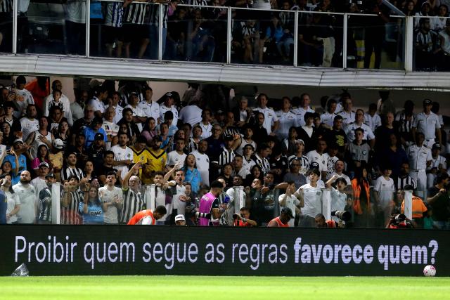 A pitchside advertisement reading “Who benefits from banning those who follow the rules?” as part of a campaign organized by the betting companies' association is seen during the Brazilian Championship Serie A football match between Santos and Flamengo at the Vila Belmiro Stadium in Santos, Brazil on October 8, 2026. (Photo by GUILHERME DIONIZIO / AFP)