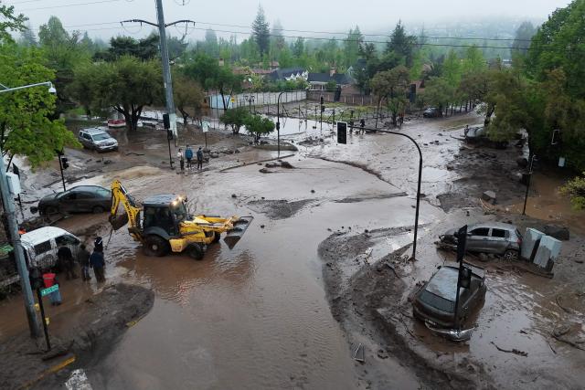 This aerial view shows heavy machinery at work and cars stranded in mud and debris following a mudslide in the Las Condes district of Santiago on October 8, 2026. (Photo by Rodrigo ARANGUA / AFP)