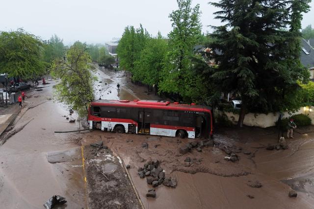 This aerial view shows a bus stranded in mud and debris following a mudslide in the Las Condes district of Santiago on October 8, 2026. (Photo by Rodrigo ARANGUA / AFP)