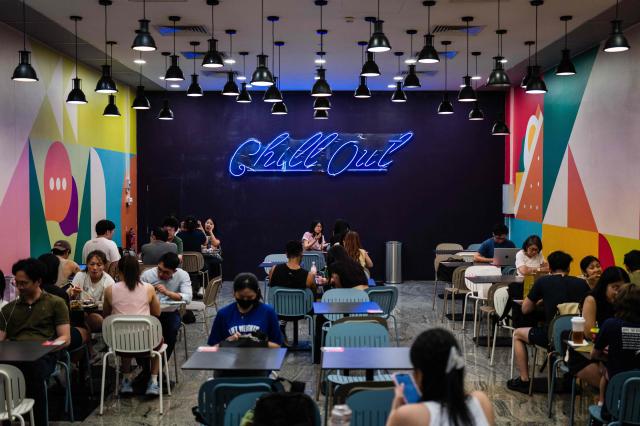 People use tables at a public seating area inside a shopping mall in Singapore on October 8, 2026. (Photo by ANTHONY WALLACE / AFP)