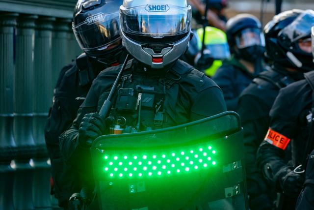 French police officers of the Repression of Violent Action Motorised Brigade (Brav-M or Brigade de repression de l'action violente motorisee) hold strobe-capable shields during a demonstration of high-school students at Place de la Bastille, in Paris, on October 8, 2026, as part of a nationwide protest movement over learning conditions. Since late September, pupils have barred the entrances to hundreds of schools, complaining of teacher absences, overloaded timetables, dilapidated classrooms and buildings ill-adapted to rising temperatures, among other grievances. (Photo by Kenzo TRIBOUILLARD / AFP)