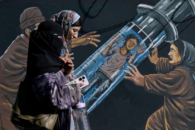 Kashmiri Muslim women walk past an anti-drugs mural in Srinagar on October 9, 2026. (Photo by Tauseef MUSTAFA / AFP)
