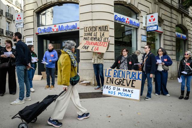 Journalists from the daily newspaper Le Bien Public, part of the Ebra group owned by Credit Mutuel bank, gather outside a Credit Mutuel bank branch to protest against the use of artificial intelligence in the group's publications in Dijon on October 9, 2026. (Photo by ARNAUD FINISTRE / AFP)