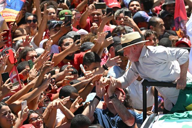 Brazil's President and presidential candidate Luiz Inacio Lula da Silva, of the Workers' Party (PT) leans over to greet supporters during a motorcade in Ceilandia, Federal District, Brazil on October 9, 2026. Lula da Silva, who has risen from the political ashes several times, is heading to a runoff election against right-wing senator Flavio Bolsonaro on October 25, after a shock second-place finish in the first-round vote. (Photo by Evaristo SA / AFP)