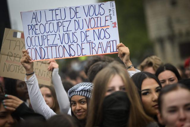 A student holds a placard reading "Instead of worrying about the veil, concern yourselves with our working conditions" as thousands of students protest over learning conditions as part of a nationwide movement in Nantes on October 9, 2026. Since late September, pupils have barred the entrances to hundreds of schools, complaining of teacher absences, overloaded timetables, dilapidated classrooms and buildings ill-adapted to rising temperatures, among other grievances. (Photo by Loic VENANCE / AFP)