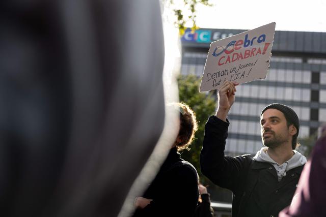 A protester holds a sign reading “Ebra-cadabra - Tomorrow a journal made by AI” as employees of the EBRA group (Est Bourgogne Rhфne Alpes), a French regional daily newspaper group, demonstrate in front of the headquarters of Crйdit Mutuel, owner of the group, for various labour issues including the rising use of AI and job cuts in Strasbourg, eastern France, on October 9, 2026. (Photo by ROMEO BOETZLE / AFP)