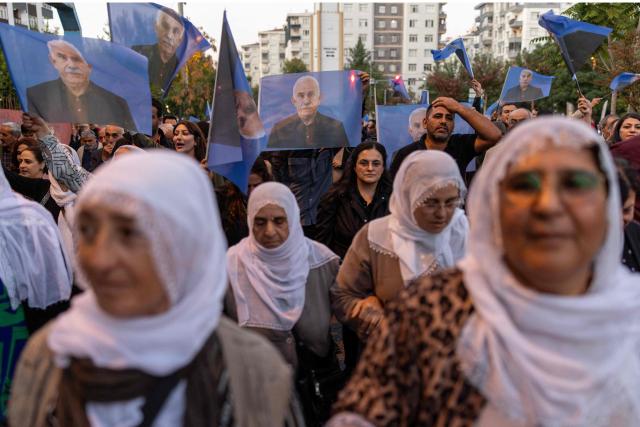 Demonstrators hold flags and posters depicting jailed leader of the Kurdistan Workers' Party (PKK) Abdullah Ocalan while taking part in a protest marking the anniversary of his expulsion from Syria in Diyarbakir on October 9, 2026. The PKK on October 6, 2026 accused the Turkish state of doing little to pursue the peace process that began in 2024, despite the Kurdish group having withdrawn all its combat forces from Turkey. Turkey's parliament in August voted through a law offering limited amnesty for militants from the Kurdistan Workers' Party (PKK) in the first legislative step to ending the conflict that has left some 50,000 people dead over decades of bloody conflict. The August law did not specify what will become of jailed PKK leader Abdullah Ocalan, 77, who has spent the past 27 years in solitary confinement on Imrali prison island near Istanbul. (Photo by Bilal Seckin / AFP)
