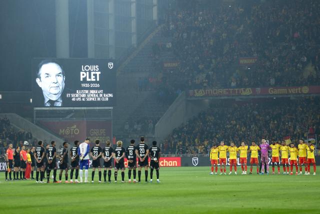 Lens' and Lyons' players line up to pay tribute to the late Lens coach Louis Plet before the French L1 football match between RC Lens and Olympique Lyonnais (OL) at the Stade Bollaert-Delelis in Lens, northern France, on October 9, 2026. (Photo by Sameer AL-DOUMY / AFP)