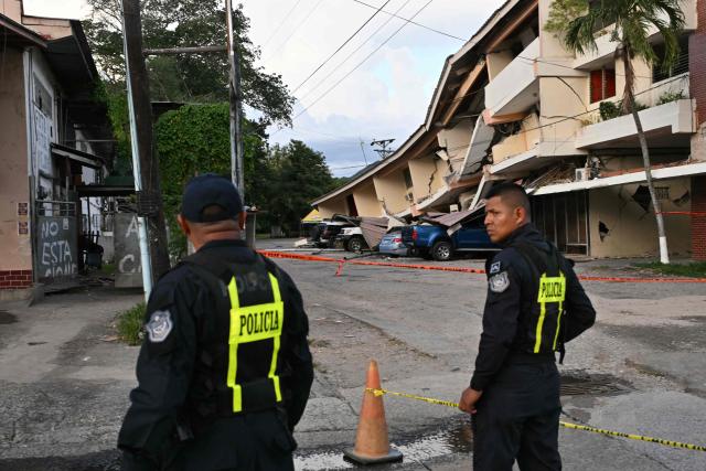 Panamanian police officers stand guard next to a collapsed building after a 7.6-magnitude earthquake struck the country, in Penonome, Panama, on October 9, 2026. According to the US Geological Survey (USGS), a magnitude 7.6 earthquake shook Panama sparking panic in the capital, though no casualties or damage have been reported so far. (Photo by MARTIN BERNETTI / AFP)