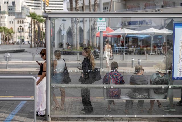 This photo taken on September 29, 2026 shows commuters waiting for the bus at a bus stop in Tel Aviv. Israel heads to the polls on October 27 in its first election since the October 7, 2023 Hamas-led attack, in what is seen as a referendum on Israel's Prime Minister Benjamin Netanyahu. Roughly 550,000 Israelis aged between 18 and 22 will be voting for the first time in October, according to Israel's Channel 12. In a recent poll commissioned by the channel, 74 percent of first-time voters described their policy views as right or centre-right -- an even higher share than the broadly right-leaning public at large. (Photo by Ilia YEFIMOVICH / AFP) / To go with 'ISRAEL-VOTE-YOUTH-PALESTINIANS-CONFLICT, REPORTAGE' by Alice Chancellor