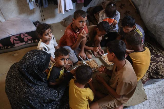 This photo taken on October 6, 2026 shows the children of Nihaya Al-Masri, a 35-year-old displaced Palestinian woman from Beit Hanoun, sharing a meal provided by a charity kitchen in Khan Yunis, in the southern Gaza Strip. Every day, Gazan mother Niyaha al-Masri spends six exhausting hours or more queueing at a community kitchen in the hope of getting some food for her family. It has been a year since a ceasefire between Hamas and Israel was supposed to allow food to flood into the ruined territory, yet the hunger crisis there persists. (Photo by Bashar Taleb / AFP) / To go with 'ISRAEL-PALESTINIANS-CONFLICT-GAZA-HUNGER, FOCUS" by AFP team in Gaza, with Anouk RIONDET in Jerusalem