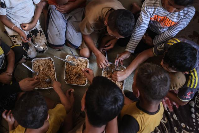 This photo taken on October 6, 2026 shows the children of Nihaya Al-Masri, a 35-year-old displaced Palestinian woman from Beit Hanoun, sharing a meal provided by a charity kitchen in Khan Yunis, in the southern Gaza Strip. Every day, Gazan mother Niyaha al-Masri spends six exhausting hours or more queueing at a community kitchen in the hope of getting some food for her family. It has been a year since a ceasefire between Hamas and Israel was supposed to allow food to flood into the ruined territory, yet the hunger crisis there persists. (Photo by Bashar Taleb / AFP) / To go with 'ISRAEL-PALESTINIANS-CONFLICT-GAZA-HUNGER, FOCUS" by AFP team in Gaza, with Anouk RIONDET in Jerusalem
