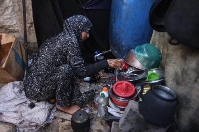 This photo taken on October 6, 2026 shows Nihaya Al-Masri, a 35-year-old displaced Palestinian woman from Beit Hanoun, doing the dishes at the makeshift shelter where she lives with her husband and their six children in Khan Yunis, in the southern Gaza Strip. Every day, Gazan mother Niyaha al-Masri spends six exhausting hours or more queueing at a community kitchen in the hope of getting some food for her family. It has been a year since a ceasefire between Hamas and Israel was supposed to allow food to flood into the ruined territory, yet the hunger crisis there persists. (Photo by Bashar Taleb / AFP) / To go with 'ISRAEL-PALESTINIANS-CONFLICT-GAZA-HUNGER, FOCUS" by AFP team in Gaza, with Anouk RIONDET in Jerusalem