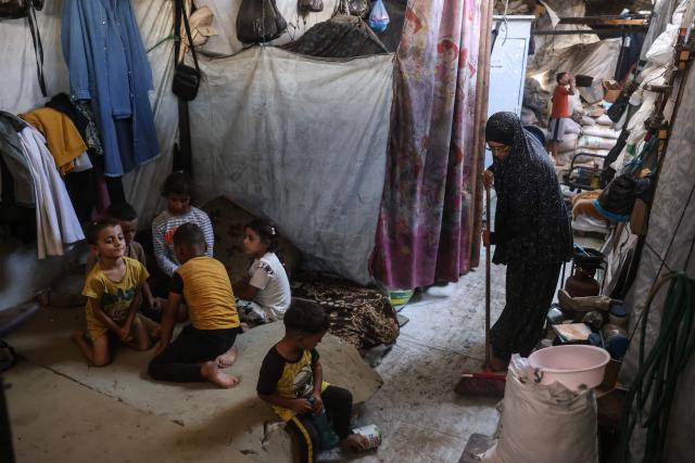 This photo taken on October 6, 2026 shows Nihaya Al-Masri, a 35-year-old displaced Palestinian woman from Beit Hanoun, sweeping the floor of the makeshift shelter where she lives with her husband and their six children in Khan Yunis, in the southern Gaza Strip. Every day, Gazan mother Niyaha al-Masri spends six exhausting hours or more queueing at a community kitchen in the hope of getting some food for her family. It has been a year since a ceasefire between Hamas and Israel was supposed to allow food to flood into the ruined territory, yet the hunger crisis there persists. (Photo by Bashar Taleb / AFP) / To go with 'ISRAEL-PALESTINIANS-CONFLICT-GAZA-HUNGER, FOCUS" by AFP team in Gaza, with Anouk RIONDET in Jerusalem