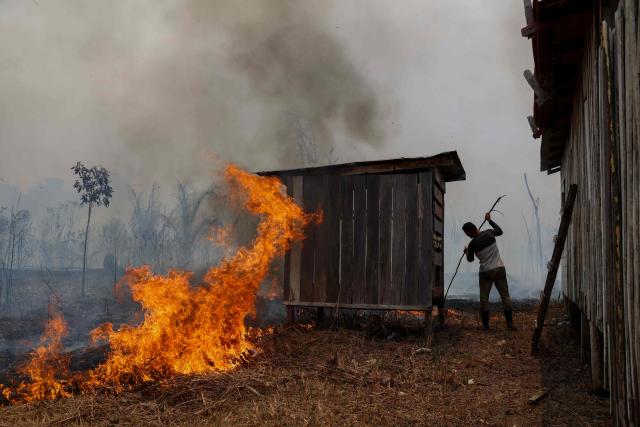 A man tries to contain a forest fire approaching a home in the rural area of Autazes, in Amazonas state, northern Brazil, on October 9, 2026. (Photo by MICHAEL DANTAS / AFP)