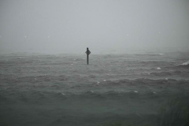 A pole sign is partially underwater by the storm surge of Hurricane Isaias in Pensacola, Florida, on October 9, 2026. Hurricane Isaias' outer bands were lashing the US Gulf Coast with heavy rain and strong winds Friday, with the category 3 storm triggering mandatory evacuations and poised to bring life-threatening storm surge when it makes landfall. (Photo by RONALDO SCHEMIDT / AFP)