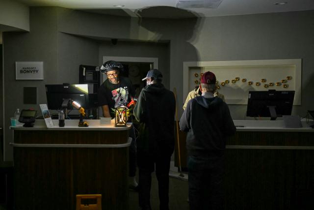 Hotel guests are assisted using flashlights as electricity went off shortly before Hurricane Isaias' landfall in Pensacola, Florida, on October 9, 2026. Hurricane Isaias' outer bands were lashing the US Gulf Coast with heavy rain and strong winds Friday, with the category 3 storm triggering mandatory evacuations and poised to bring life-threatening storm surge when it makes landfall. (Photo by RONALDO SCHEMIDT / AFP)