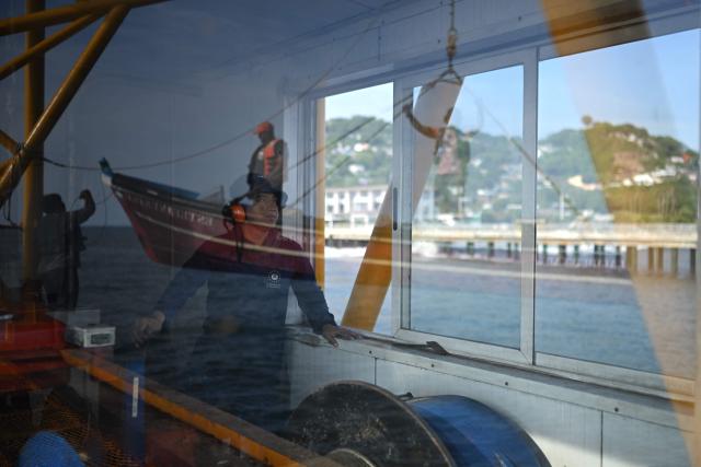 A port worker helps fishermen bring their boat to the pier at the port of La Libertad, El Salvador, on October 9, 2026. (Photo by Marvin RECINOS / AFP)
