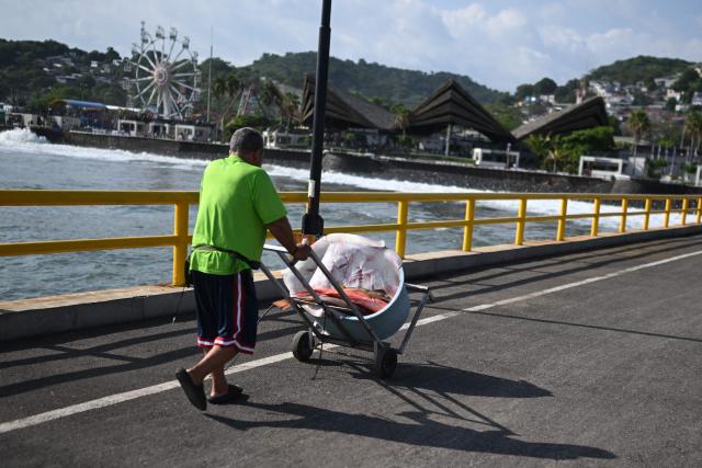 A man transports a stingray and several fish he purchased in a handcart along the waterfront at the port of La Libertad, El Salvador, on October 9, 2026. (Photo by Marvin RECINOS / AFP)