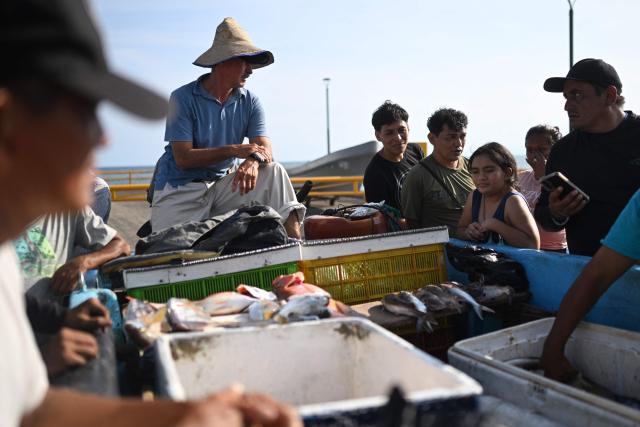Fishermen sell their catch to tourists and other buyers at the pier of the port of La Libertad, El Salvador, on October 9, 2026. (Photo by Marvin RECINOS / AFP)