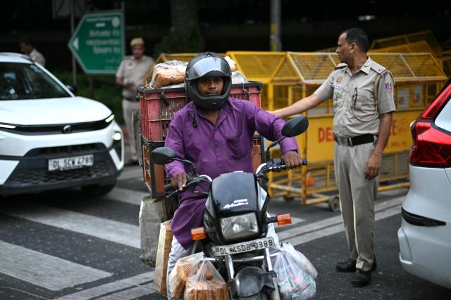 A vendor rides past a police checkpoint ahead of a protest by the youth-led Cockroach Janata Party (CJP) demanding the resignation of India’s Chief Election Commissioner over alleged "special intensive revision” (SIR) voter-roll irregularities, in New Delhi on October 10, 2026. India deployed thousands of police in its capital and restricted transportation in and around Delhi ahead of mass demonstrations on October 10 demanding the resignation of the country's election chief over alleged voter-roll irregularities. (Photo by Manan VATSYAYANA / AFP)