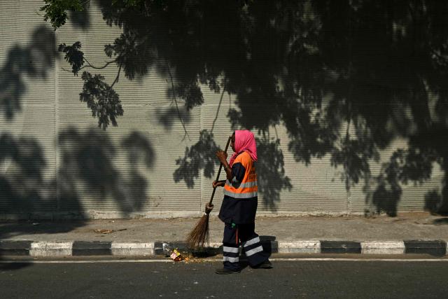 A sanitary worker sweeps a street in Chennai on October 10, 2026. (Photo by R.Satish BABU / AFP)