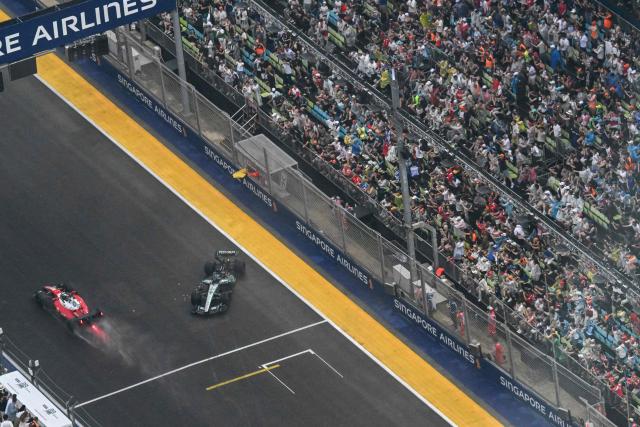 A safety car (L) is deployed after Mercedes' British driver George Russell (C) suffered a crash during the sprint race ahead of the Formula One Singapore Grand Prix at the Marina Bay Street Circuit in Singapore on October 10, 2026. (Photo by ROSLAN RAHMAN / AFP)