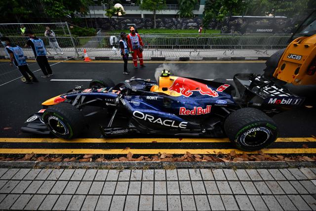 Track marshals stand beside the car of Red Bull Racing's French driver Isack Hadjar after it was extracted during the sprint race ahead of the Formula One Singapore Grand Prix at the Marina Bay Street Circuit in Singapore on October 10, 2026. (Photo by ANTHONY WALLACE / AFP)