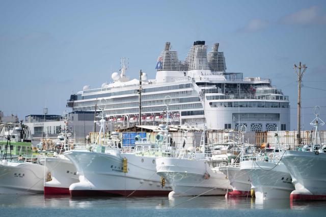 A large cruise ship is seen near fishing boats at the main fishing port in Naha, Okinawa prefecture on October 10, 2026. (Photo by ANDREW CABALLERO-REYNOLDS / AFP)