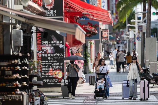 Tourists pass shops in downtown Naha, Okinawa prefecture on October 10, 2026. (Photo by ANDREW CABALLERO-REYNOLDS / AFP)