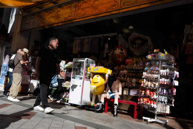 Tourists pass shops in downtown Naha, Okinawa prefecture on October 10, 2026. (Photo by ANDREW CABALLERO-REYNOLDS / AFP)