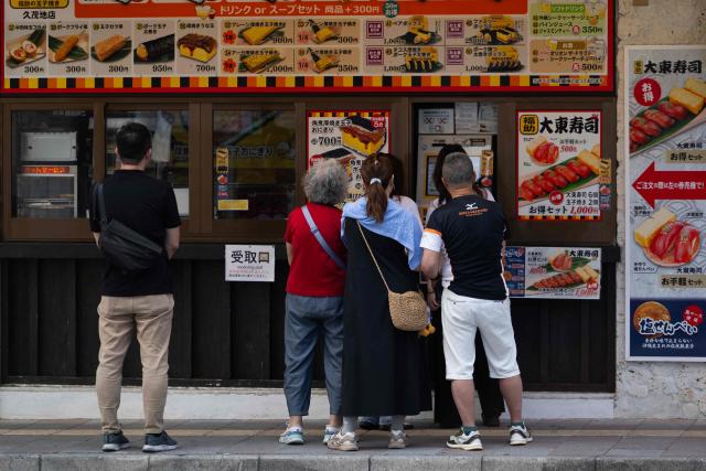 Tourist order breakfast at a kiosk for a restaurant in downtown Naha on October 10, 2026. (Photo by ANDREW CABALLERO-REYNOLDS / AFP)
