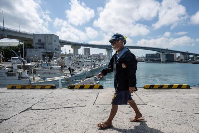 A fisherman walks near fishing boats at the main fishing port in  Naha, Okinawa prefecture on October 10, 2026. (Photo by ANDREW CABALLERO-REYNOLDS / AFP)