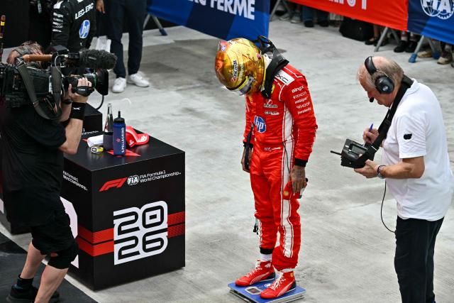 Ferrari's British driver Lewis Hamilton (C) measures his weight at the end of the sprint race ahead of the Formula One Singapore Grand Prix at the Marina Bay Street Circuit in Singapore on October 10, 2026. (Photo by ANTHONY WALLACE / AFP)