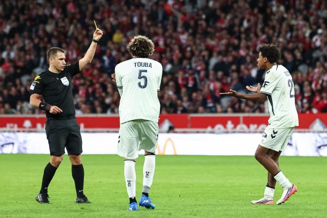 Le Havre's French defender #20 Djibril Ouziad (R) as French referee Bastien Dechepy (L) shows him a yellow card during the French L1 football match between Lille LOSC and Le Havre AC at the Stade Pierre-Mauroy in Villeneuve-d'Ascq, northern France, on October 10, 2026. (Photo by Sameer Al-DOUMY / AFP)
