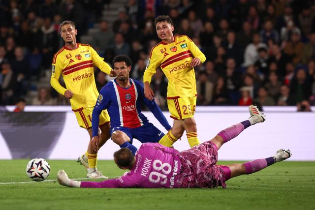 Le Mans' French goalkeeper #98 Nicolas Kocik (bottom) dives to save a shot from PSG's French midfielder #33 Warren Zaire-Emery (C) during the French L1 football match between Paris Saint-Germain (PSG) and Le Mans FC at the Parc des Princes stadium in Paris on October 10, 2026. (Photo by FRANCK FIFE / AFP)
