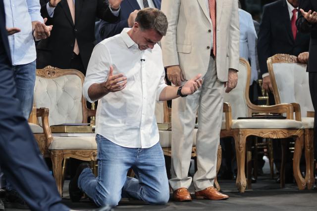 Brazilian senator and Liberal Party (PL) presidential candidate Flavio Bolsonaro prays during the official celebration marking the 100th anniversary of the Assembly of God (Madureira Ministry) at the Maracanazinho Gymnasium in Rio de Janeiro, Brazil, on October 10, 2026. (Photo by Douglas SHINEIDR / AFP)