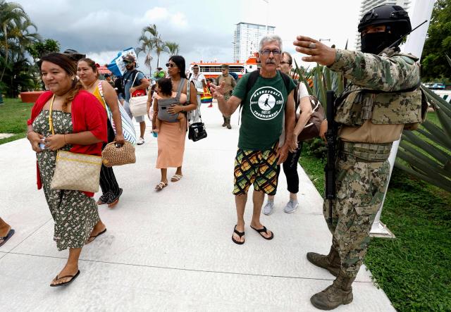 A Mexican Navy member directs evacuees from the community of Yelapa after they disembark from a ferry at the 12th Naval Zone facilities in Puerto Vallarta, Jalisco state, Mexico, on October 10, 2026, ahead of the potential impact of Hurricane Simon. Hurricane Simon strengthened into a powerful Category 4 storm as it moved toward Mexico's west coast, where it was expected to make landfall late on October 10 or early on October 11. (Photo by ULISES RUIZ / AFP)