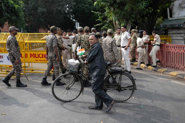 A man pushing his cycle walks past a temporary checkpoint amid ongoing protests demanding the resignation of India's Chief Election Commissioner Gyanesh Kumar over alleged voter roll irregularities linked to the "special intensive revision" (SIR), near Jantar Mantar in New Delhi on October 11, 2026. A New Delhi court ordered on October 11 the release of three leaders of the "cockroach" movement, including its founder Abhijeet Dipke, their lawyer said, a day after they were detained. (Photo by Sajjad HUSSAIN / AFP)